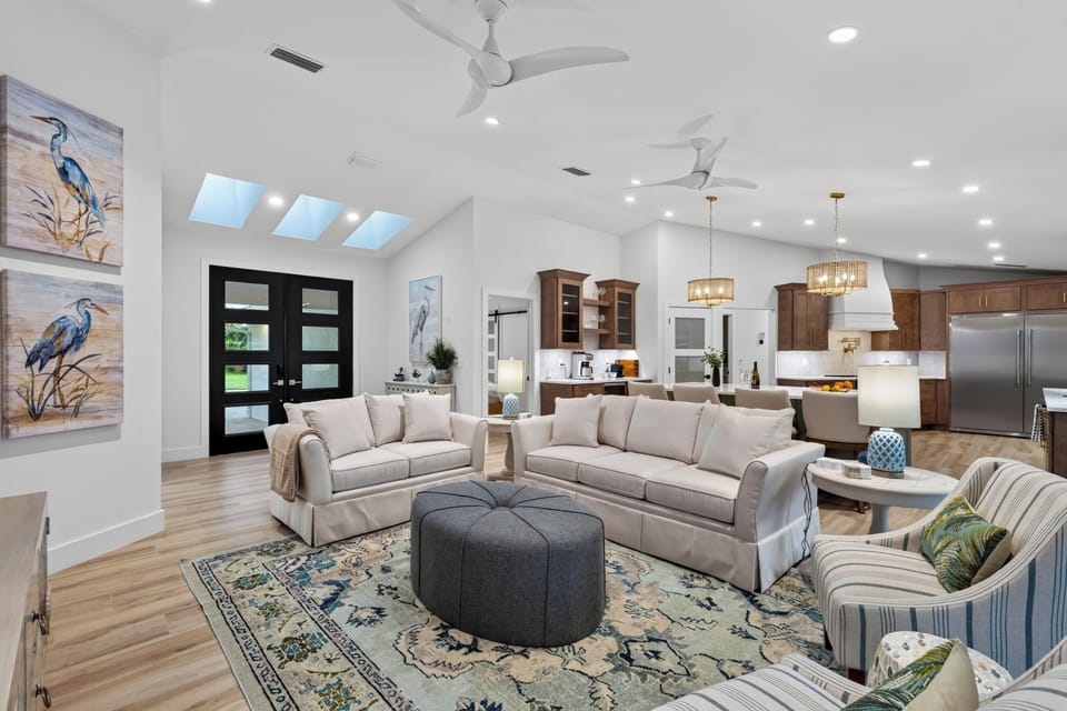 Spacious open living area showcasing light wood flooring and plush seating.