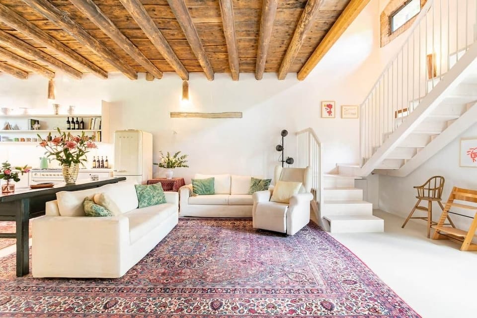 Living area next to big kitchen with second wooden staircase to first floor