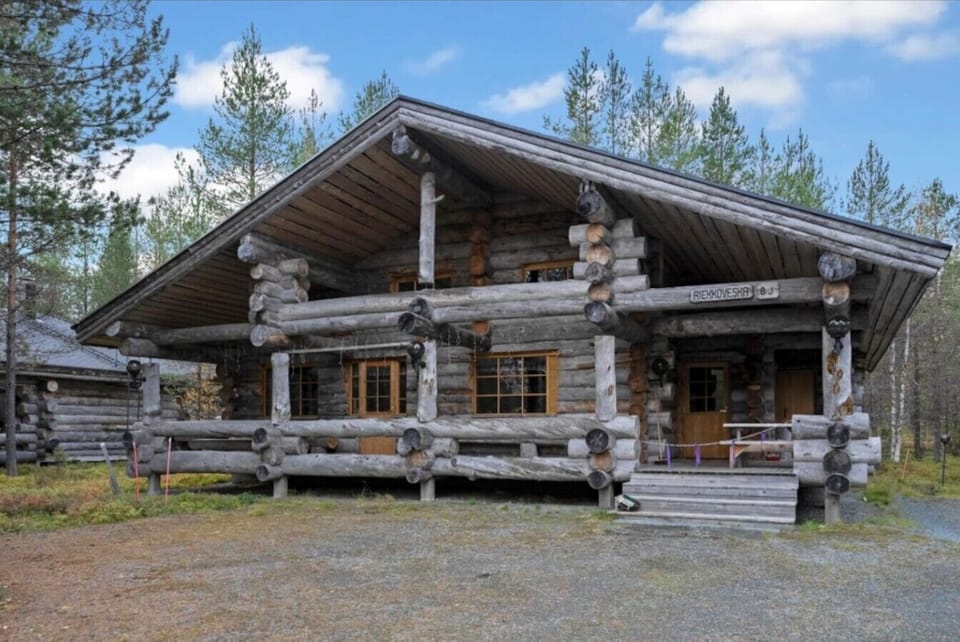 Traditional kelo-log villa with a covered front porch, surrounded by pine forest.