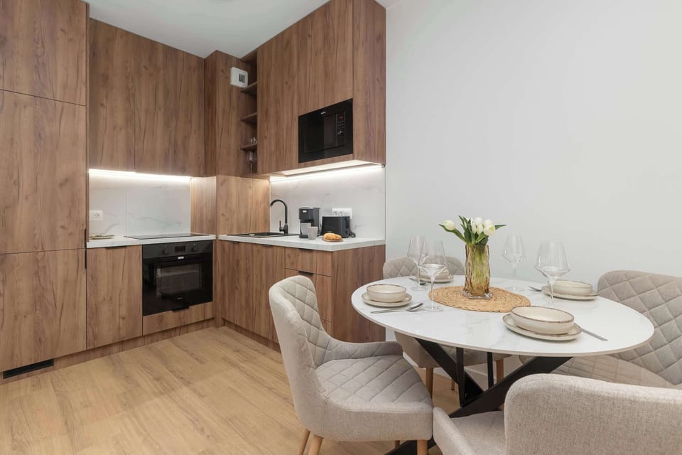 A dining area with a round table next to a modern wooden kitchen.
