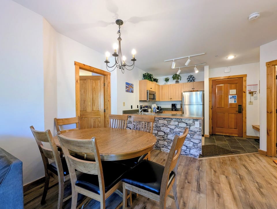 Gather around your spacious dining table under warm chandelier light, with a fully equipped kitchen just steps away—perfect for sharing meals and memories together.