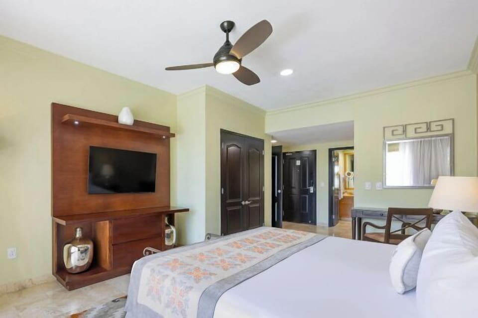 Bright, spacious bedroom with TV, ceiling fan, and elegant finishes