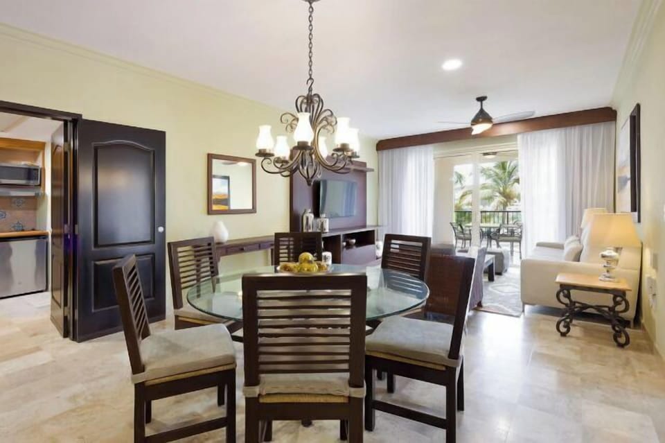 Bright dining-living space with balcony, tropical views, and seating for 6