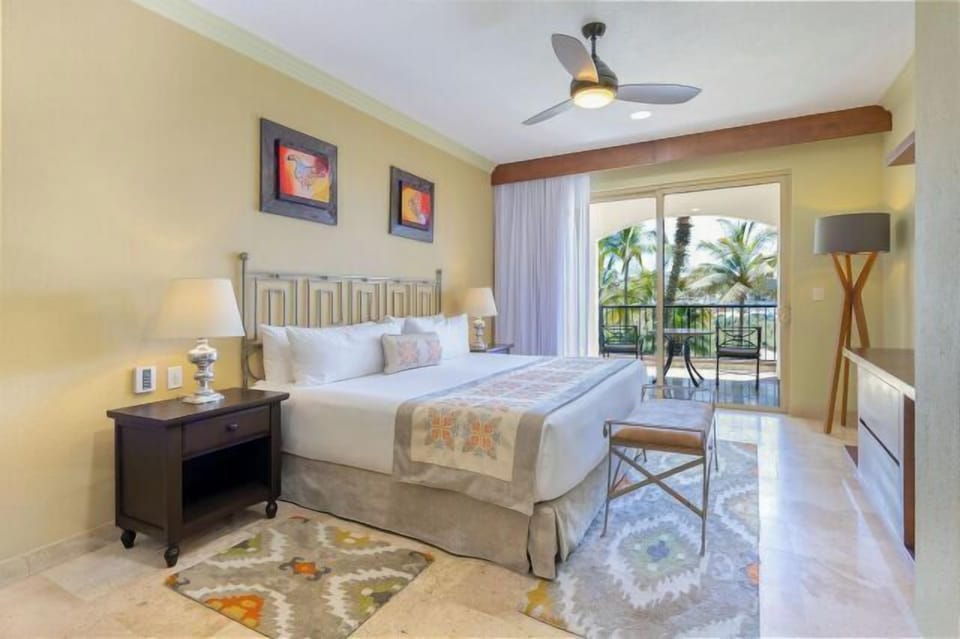 Bright king bedroom with private balcony and tropical palm views