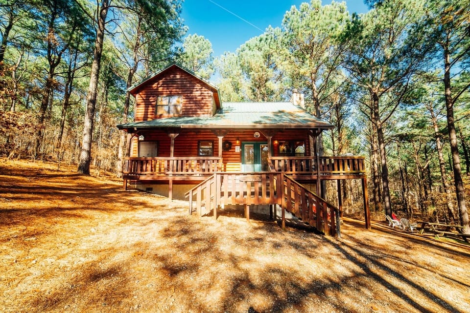 A charming log cabin nestled among towering pines, featuring a spacious deck where the surrounding forest becomes part of your daily retreat.