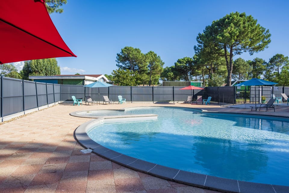 Cool off under the red shade sail beside the round outdoor pool.
