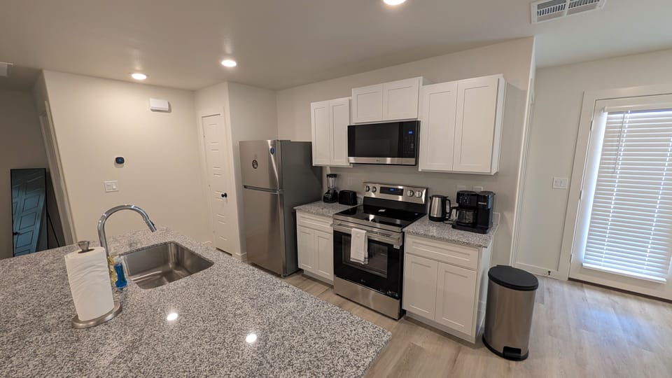 Bright modern kitchen with granite island and stainless appliances