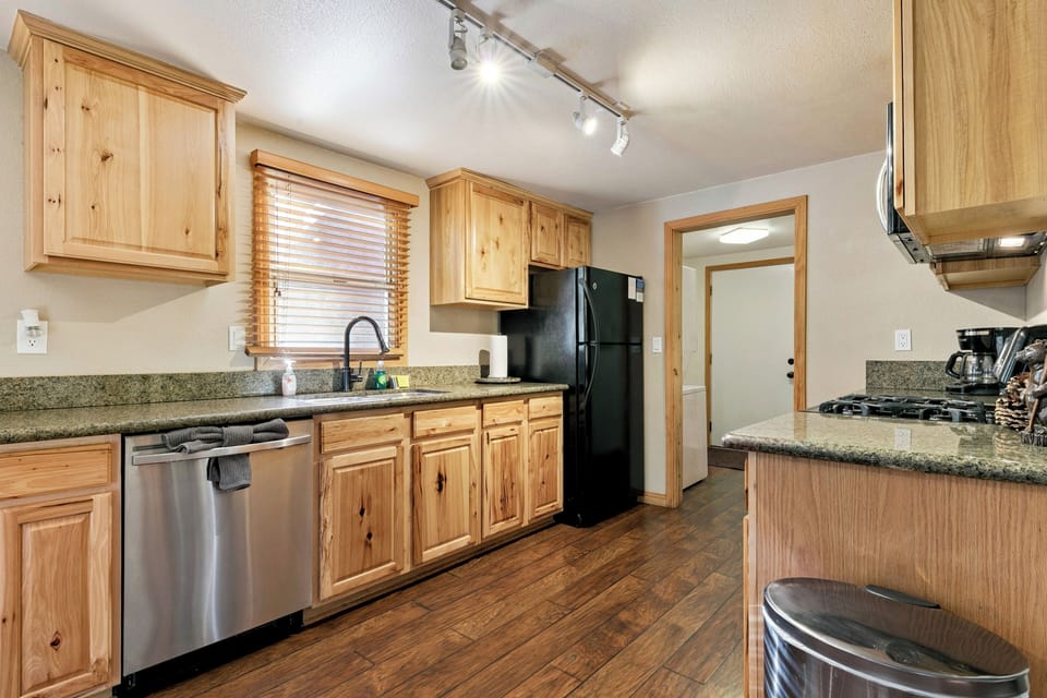 Prepare meals with ease in the kitchen featuring warm pine cabinetry, dark granite countertops, and full-size appliances.