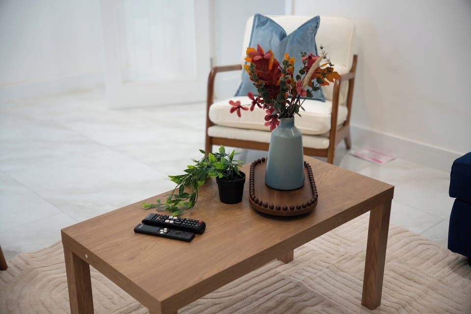 Living Room: Bright and airy seating area with a comfortable wooden coffee table, fresh florals, and plush furnishings p