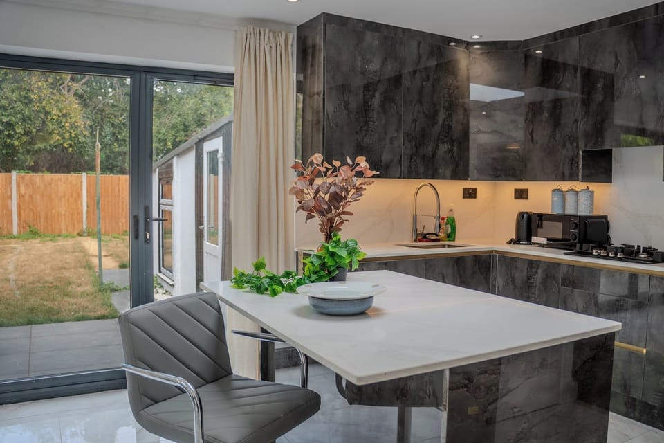 Kitchen and Dining Area: Modern space with striking dark cabinetry, warm wooden worktops, and easy access to the garden 