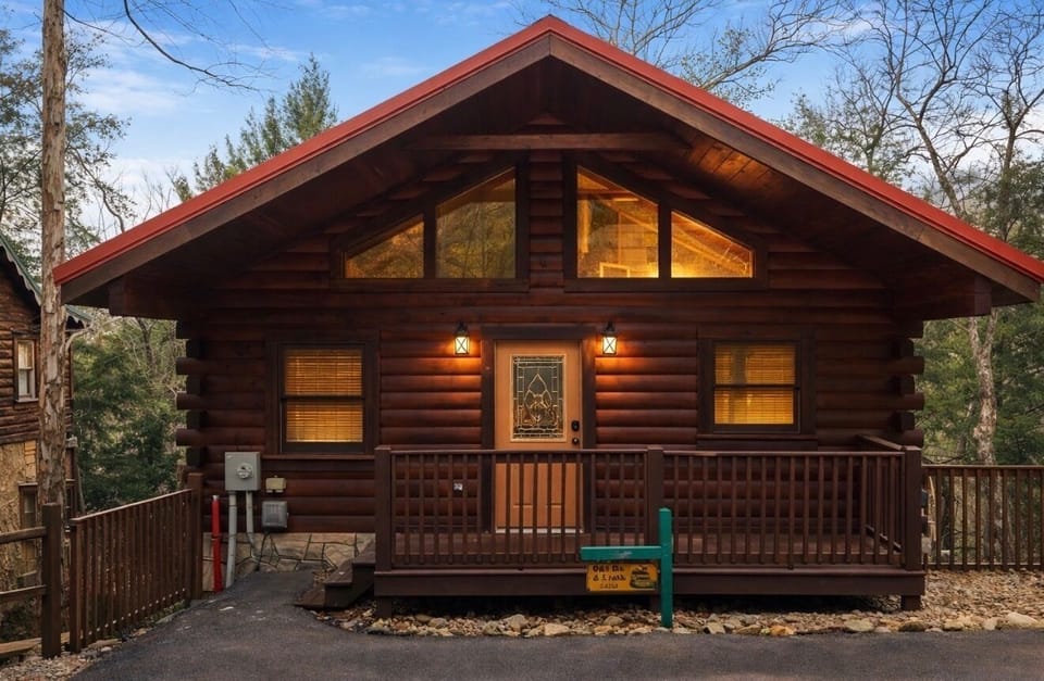 Charming log cabin with a warm, inviting glow, nestled among the trees. Enjoy a peaceful private setting, cozy front porch, and classic mountain cabin feel—perfect for couples seeking a relaxing, romantic escape.