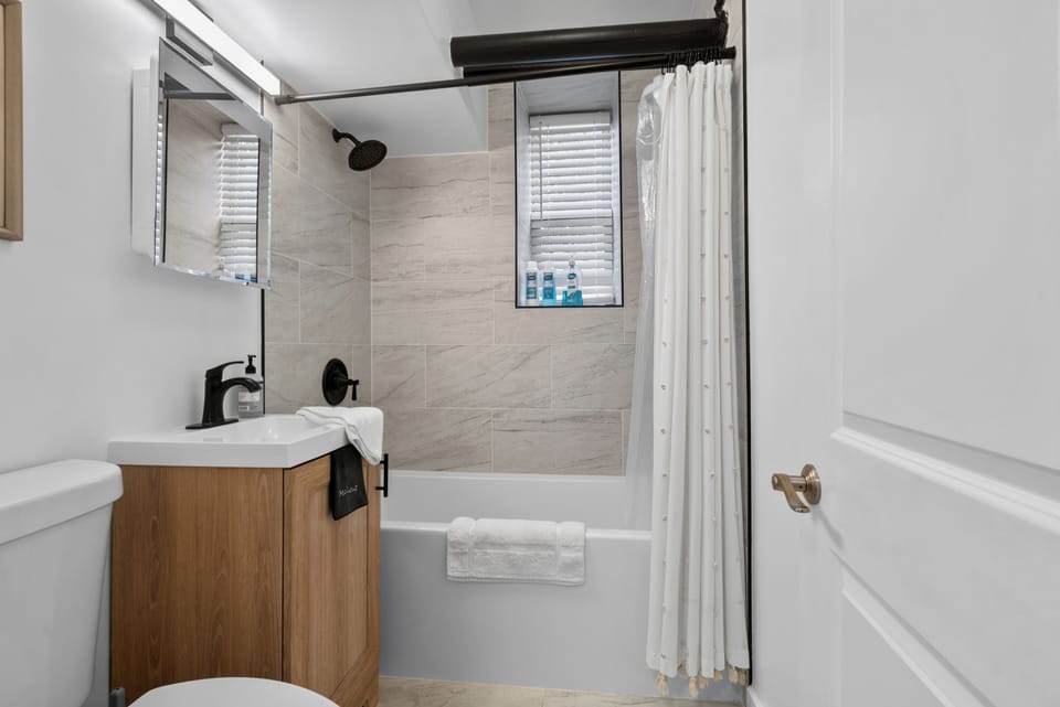 Bright modern bathroom with tiled tub-shower and stylish black fixtures