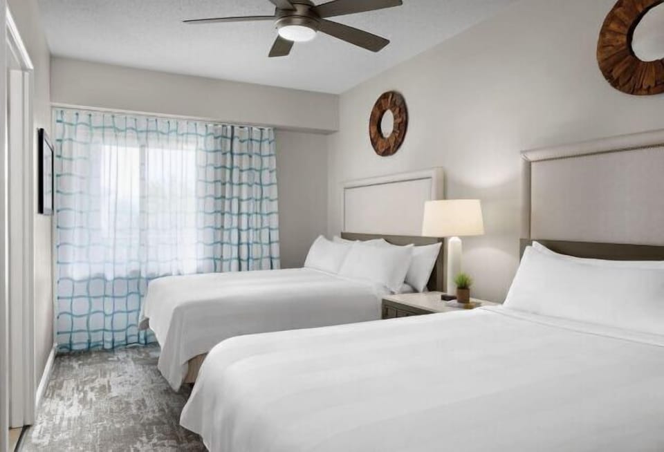 Bright double-queen bedroom with natural light and clean, modern style