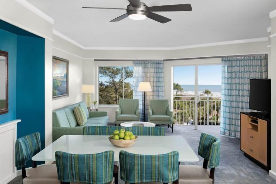 Bright coastal living room with ocean-view balcony and airy dining space