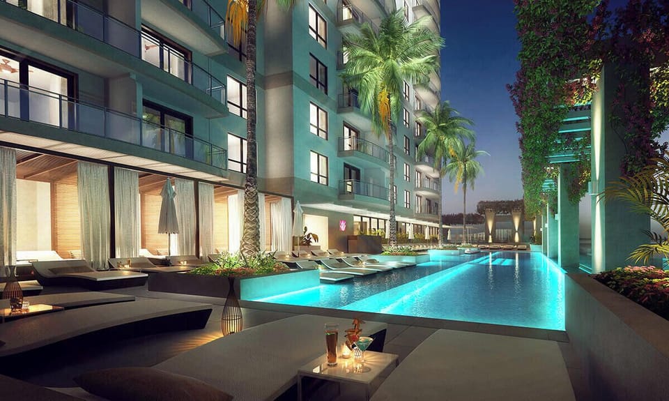 Resort-style illuminated pool with cabanas, loungers, and tropical ambiance