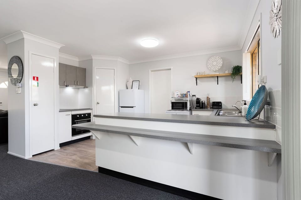 Bright open kitchen with long breakfast bar and full appliances including hotplate, oven, rangehood, fridge, freezer, dishwasher and filtered water