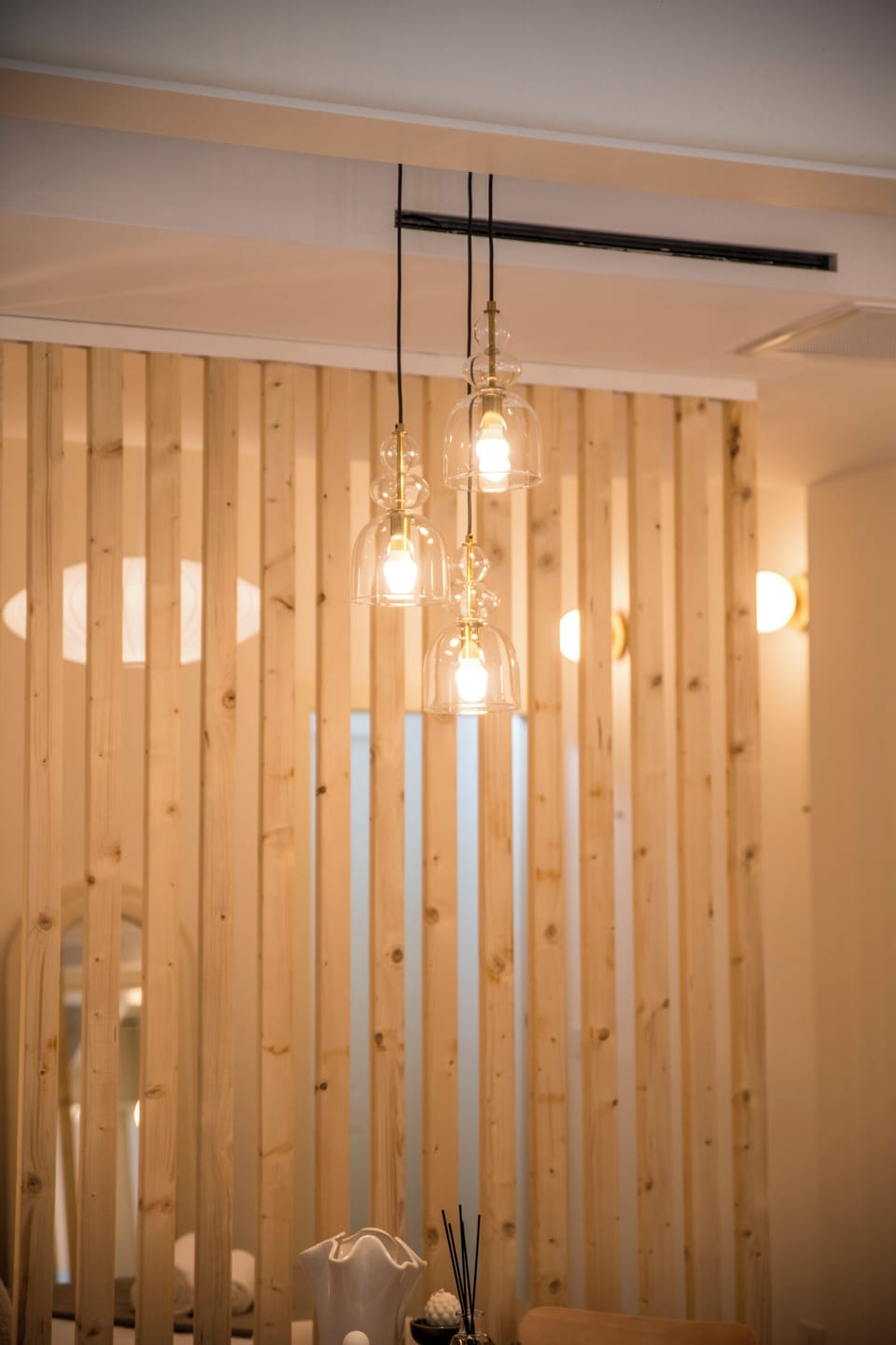 Warm pendants and wood slat divider create a cozy, modern vibe.