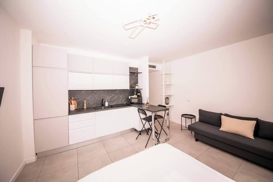Bright modern living area with kitchenette, dining/work table, Smart TV, neutral tones and clean Milanese design.
