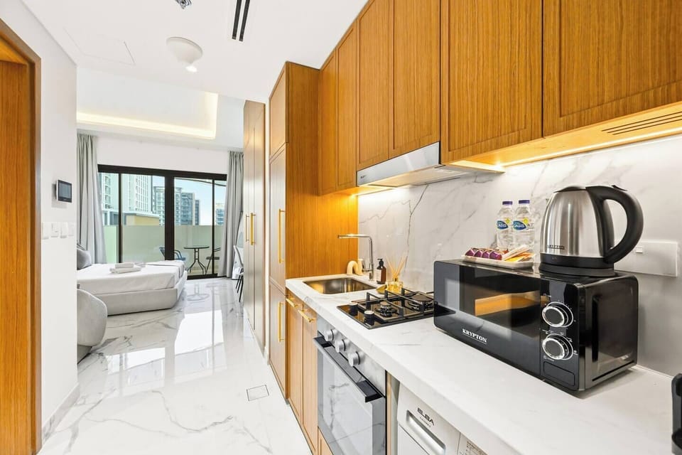 Modern brand-new kitchen with warm wooden cabinets, marble backsplash, and full amenities — including oven, washing machine, microwave, kettle, and Nespresso coffee maker — designed for a stylish and comfortable stay.