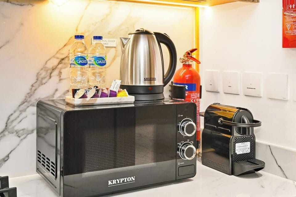 Modern brand-new kitchen with warm wooden cabinets, marble backsplash, and full amenities — including oven, washing machine, microwave, kettle, and Nespresso coffee maker — designed for a stylish and comfortable stay.