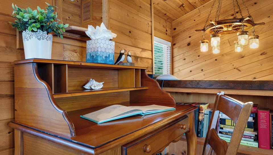 Find your creative flow at this charming wooden desk, surrounded by warm cabin vibes and soft lighting for inspiring work sessions.