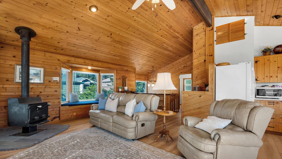 Unwind in your cozy living room with warm wood paneling, comfortable leather seating, and a crackling fireplace to complete your perfect retreat.
