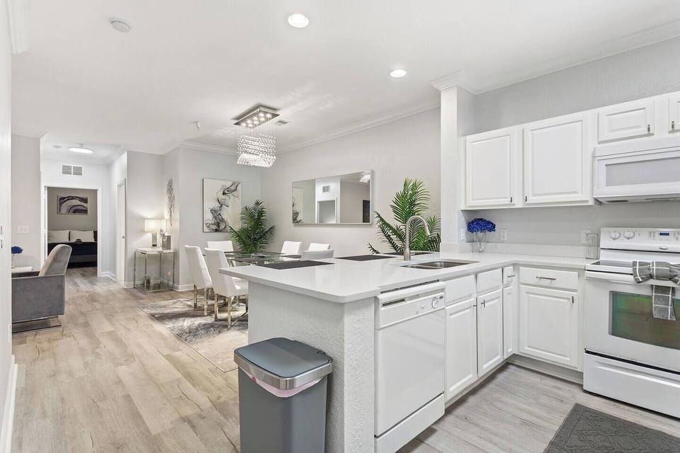 Cook and connect in this open-concept kitchen featuring a full-size fridge, stove, microwave, and dishwasher. The dining table seats six, with three additional bar stools at the counter—perfect for family meals or casual gatherings.