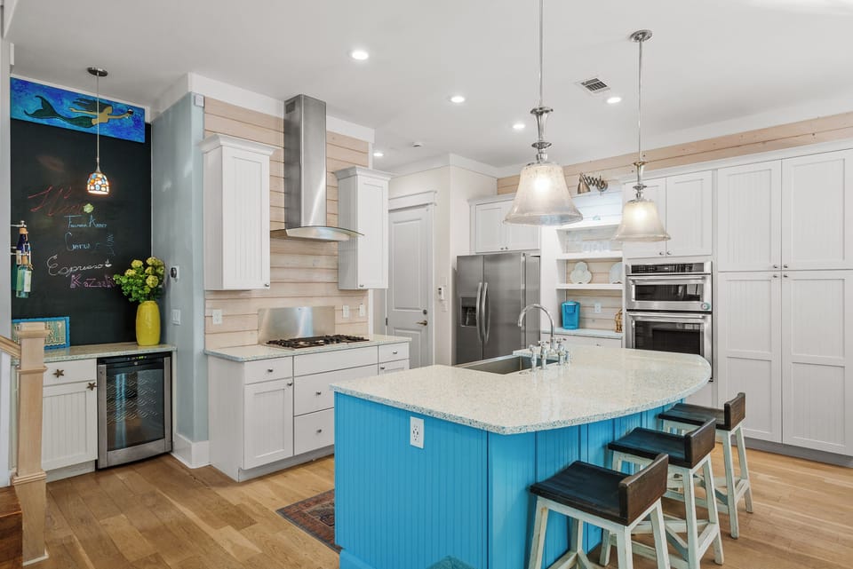 A proper cook's kitchen: gas range under a stainless hood, full size refrigerator, and a deep blue island with room to actually spread out.