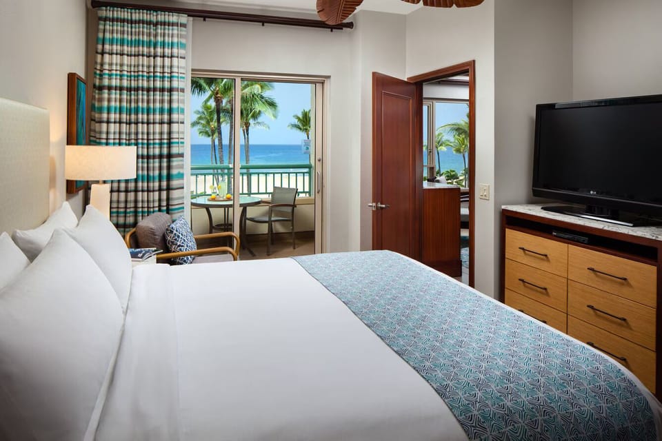 Bright ocean-view bedroom with private balcony and tropical scenery