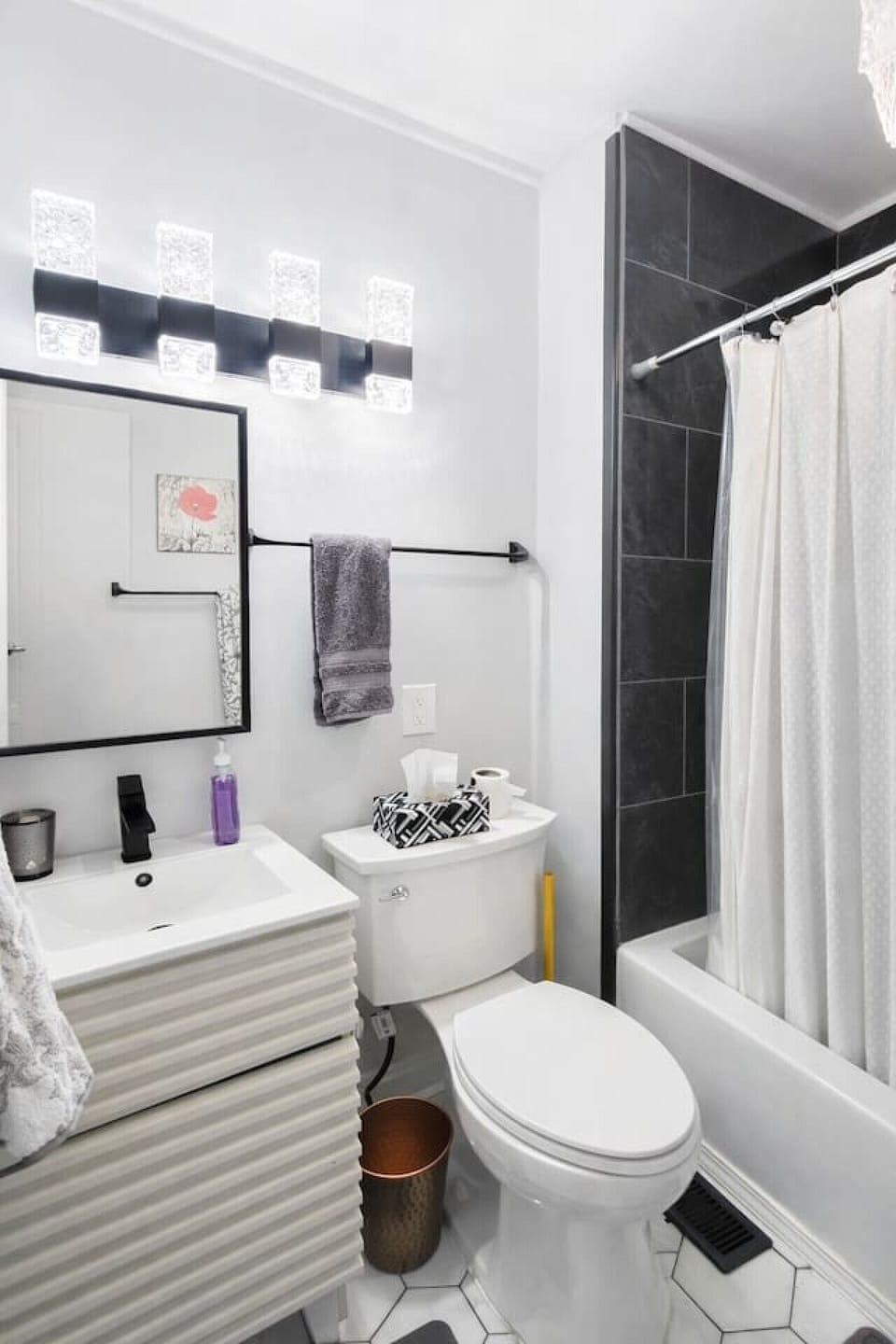 The clean and modern full bathroom features a bright, well-lit vanity and a full-size shower and tub combination, fully stocked with fresh towels and essential toiletries to provide a refreshing start to your daily routine.