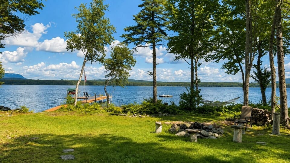 Beautiful lakefront yard featuring a private dock, fire pit, hammock, and stunning water views.