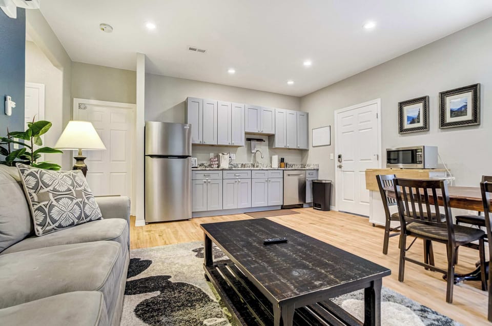 Soft gray walls and crisp white trim keep the living room feeling calm and uncluttered. A slatted wood coffee table with an open lower shelf centers the rug, framed by seating that stays comfortable well into the evening.