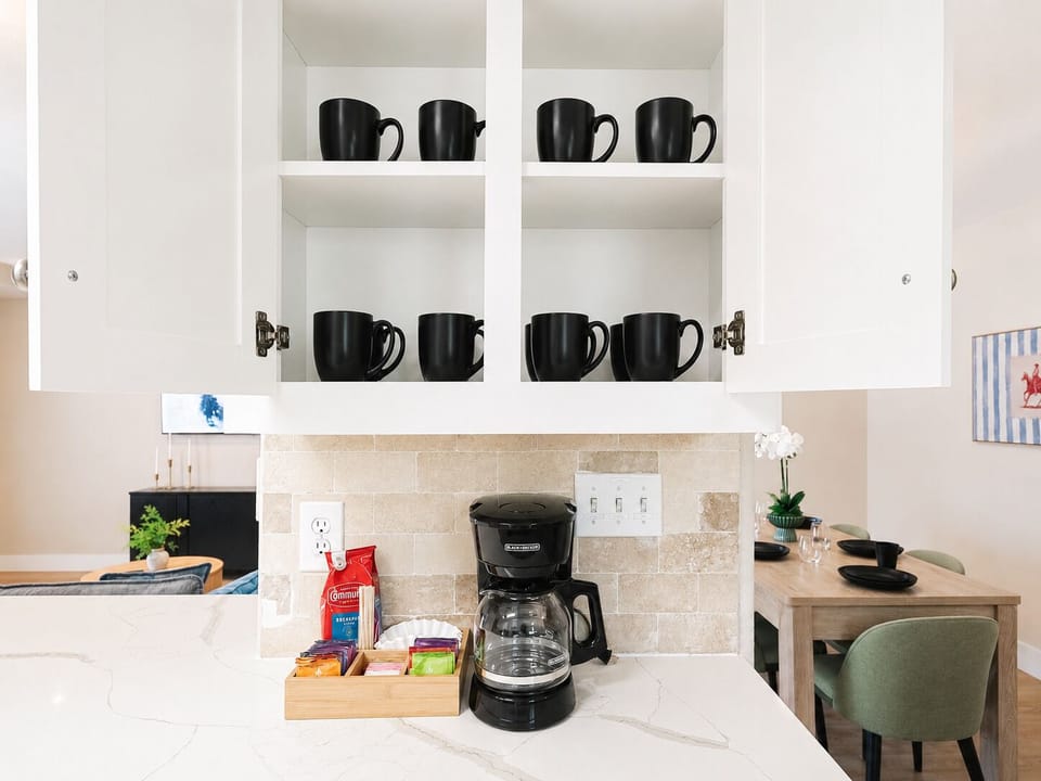Bright kitchen coffee station with stocked mugs and guest-ready beverage setup