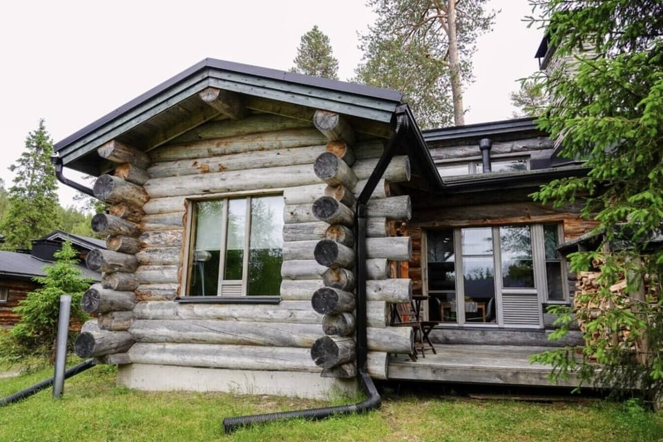 Log-built end unit of the terraced house, surrounded by greenery in summer.