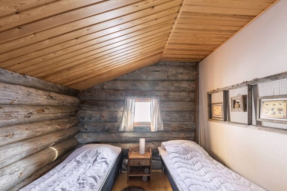 Loft bedroom with two single beds set against traditional log walls.