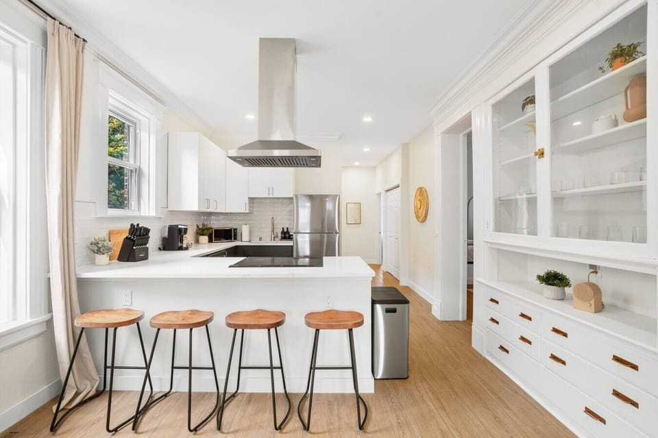 Spacious kitchen with island seating for four, glass-front built-ins, and abundant natural light