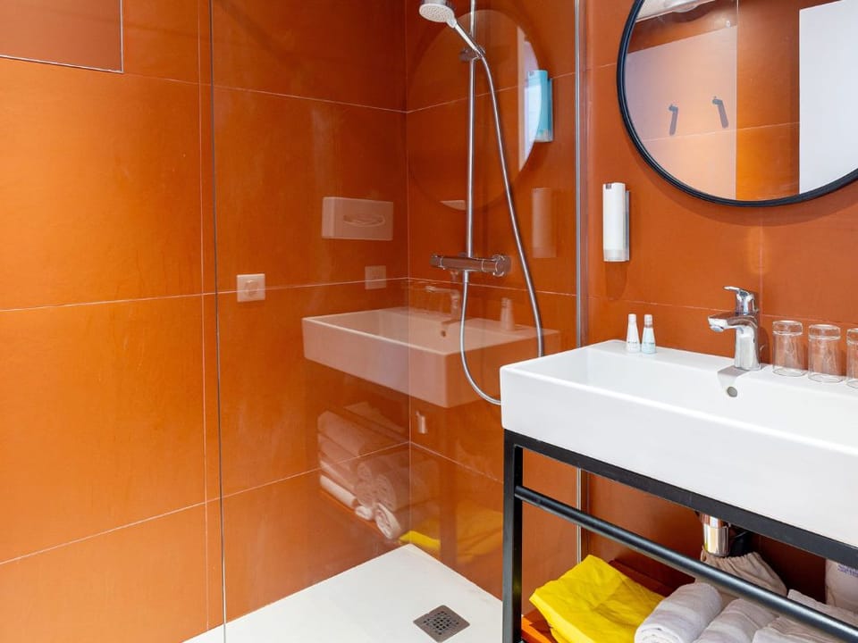 Bathroom with a shower, round mirror, and towels.