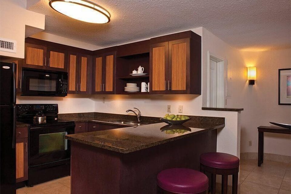 Modern kitchen with granite island, bar seating, and warm wood finishes