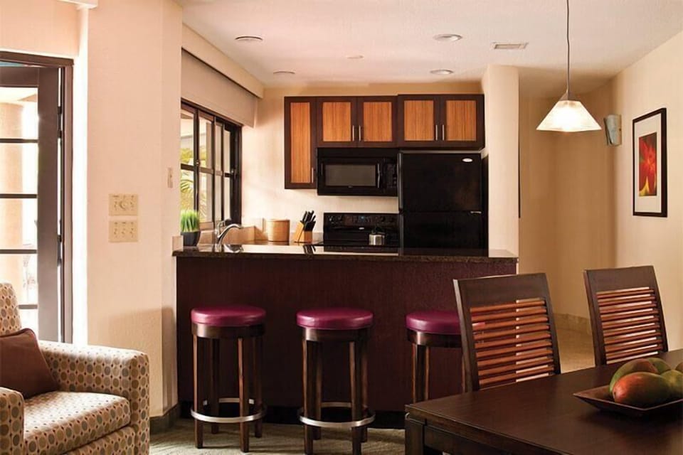 Open kitchen with breakfast bar, dining space, and warm modern finishes