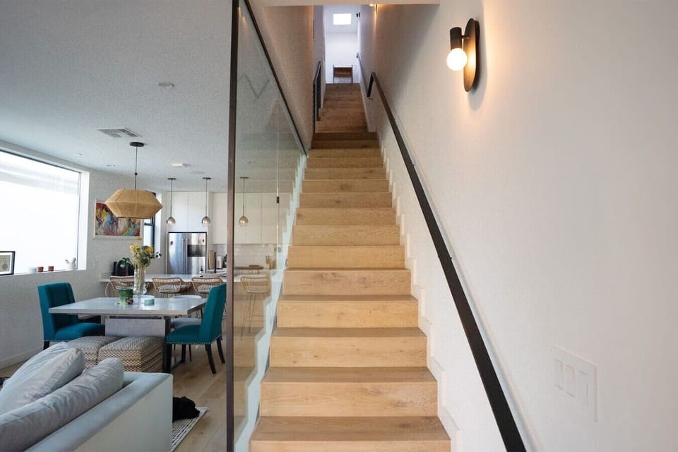 Open staircase · Floor-to-ceiling artwork · Glass railing · Modern architecture · Natural lighting · Four-story layout