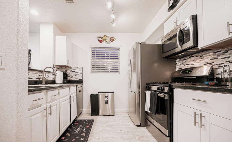 Modern galley kitchen with stainless steel, gas range, and laundry.