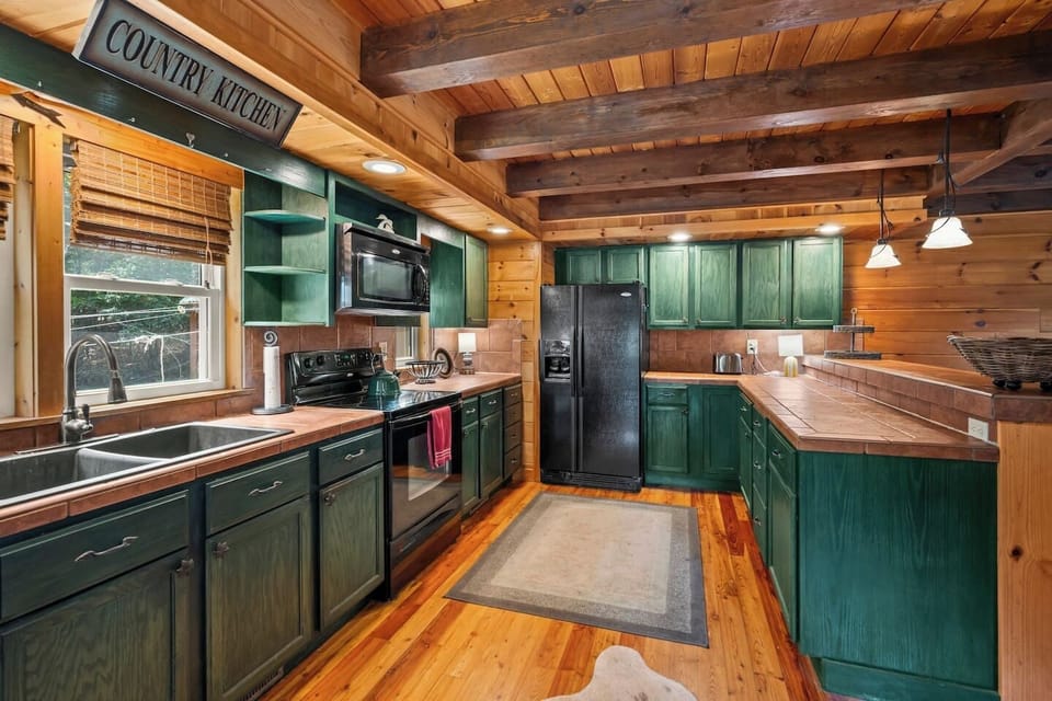 A warm, cabin‑style kitchen with a double‑door fridge, dishwasher, microwave, and a spacious bar area—perfect for gathering after long days at TIEC or exploring the mountains.