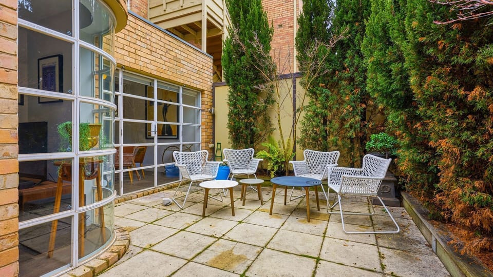 Charming private patio area surrounded by lush greenery and outdoor seating.