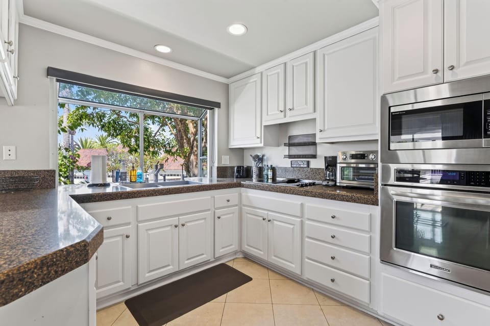 A well-equipped kitchen workspace with generous counters and a sunlit garden window.
