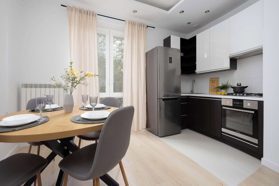 Modern kitchenette with dark cabinets and built-in appliances connected to the dining area.