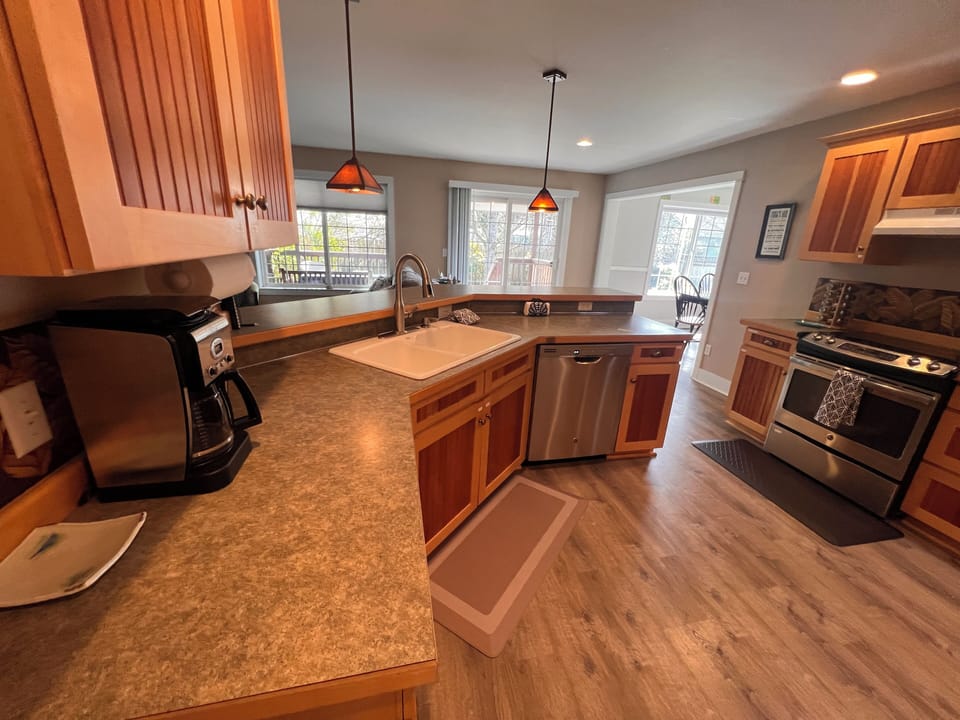 Your fully equipped kitchen features warm wood cabinetry, granite countertops, stainless steel appliances, and a bright breakfast bar where morning coffee feels like a home ritual.
