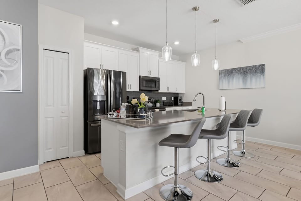 Fully equipped kitchen with a large island, breakfast seating, and stainless-steel appliances.