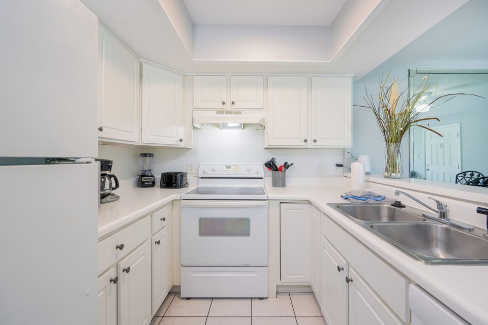 White cabinetry surrounds the stove where you prepare meals and gather around the breakfast bar in the kitchen