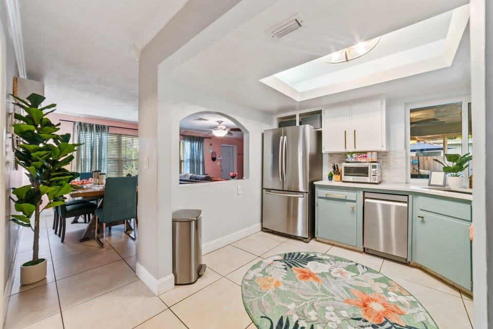 Modern Kitchen & Prep Station: Cook family meals with ease in this fully equipped kitchen, highlighting high-end stainless steel appliances, a spacious double-door refrigerator, sleek quartz countertops, custom sage cabinetry, and open sightlines into the
