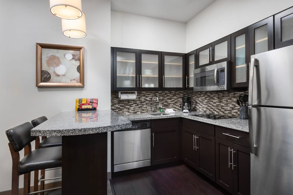 Modern kitchen with dark cabinetry, granite countertop, and stainless appliances.